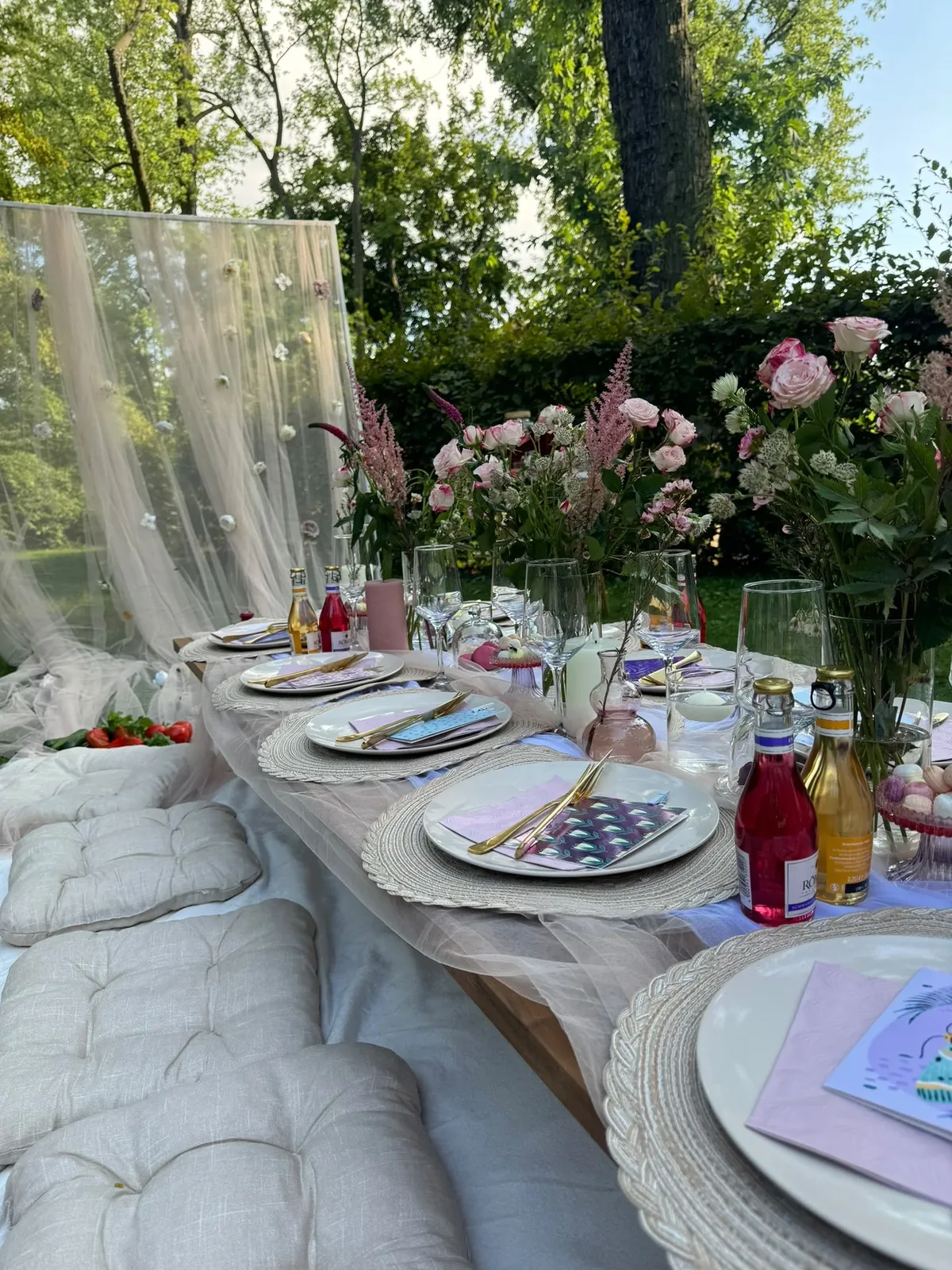 Picknicktisch mit rosa Blumen und Geschirr
